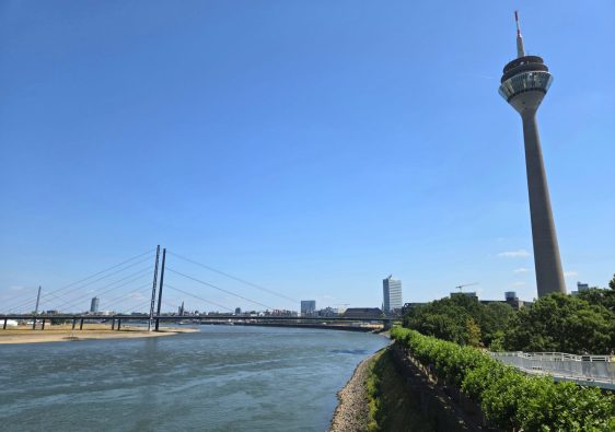 Qué ver en Düsseldorf: Rheinturm junto al río con un cielo azul de fondo